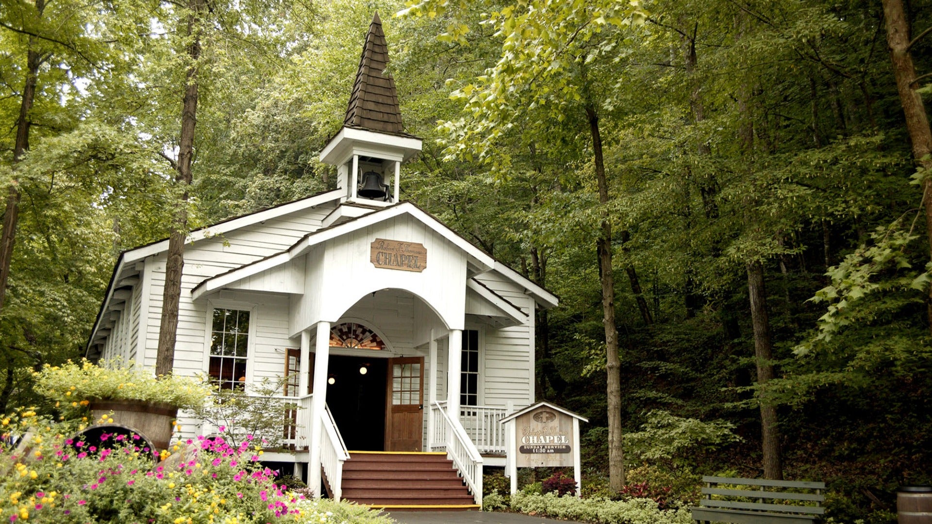 a chapel in the woods surrounded by trees and flowers