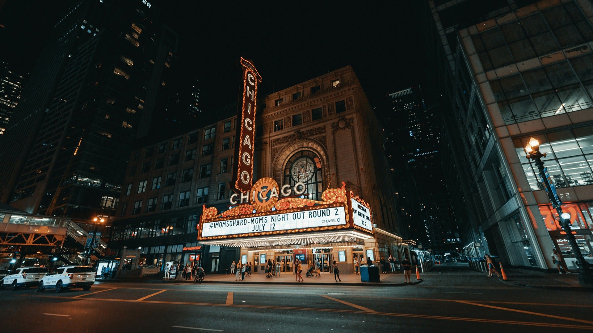 a theater with large signages and people walking around it