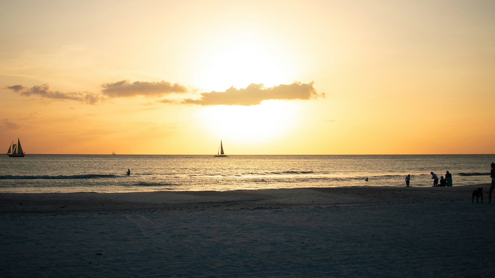 people on the beach with the sunset behind them