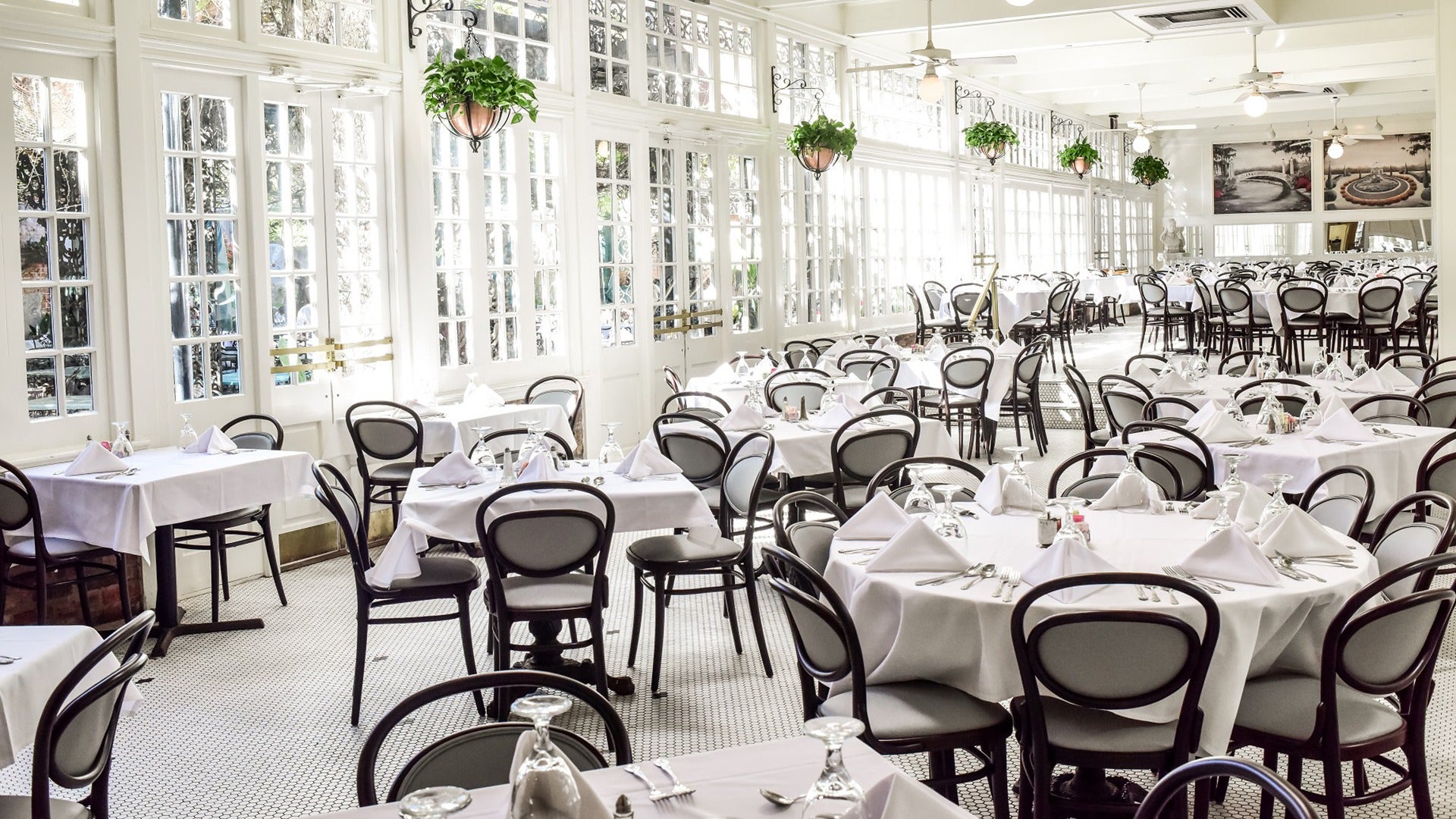 a dining room with multiple tables and chairs draped in white tablecloths