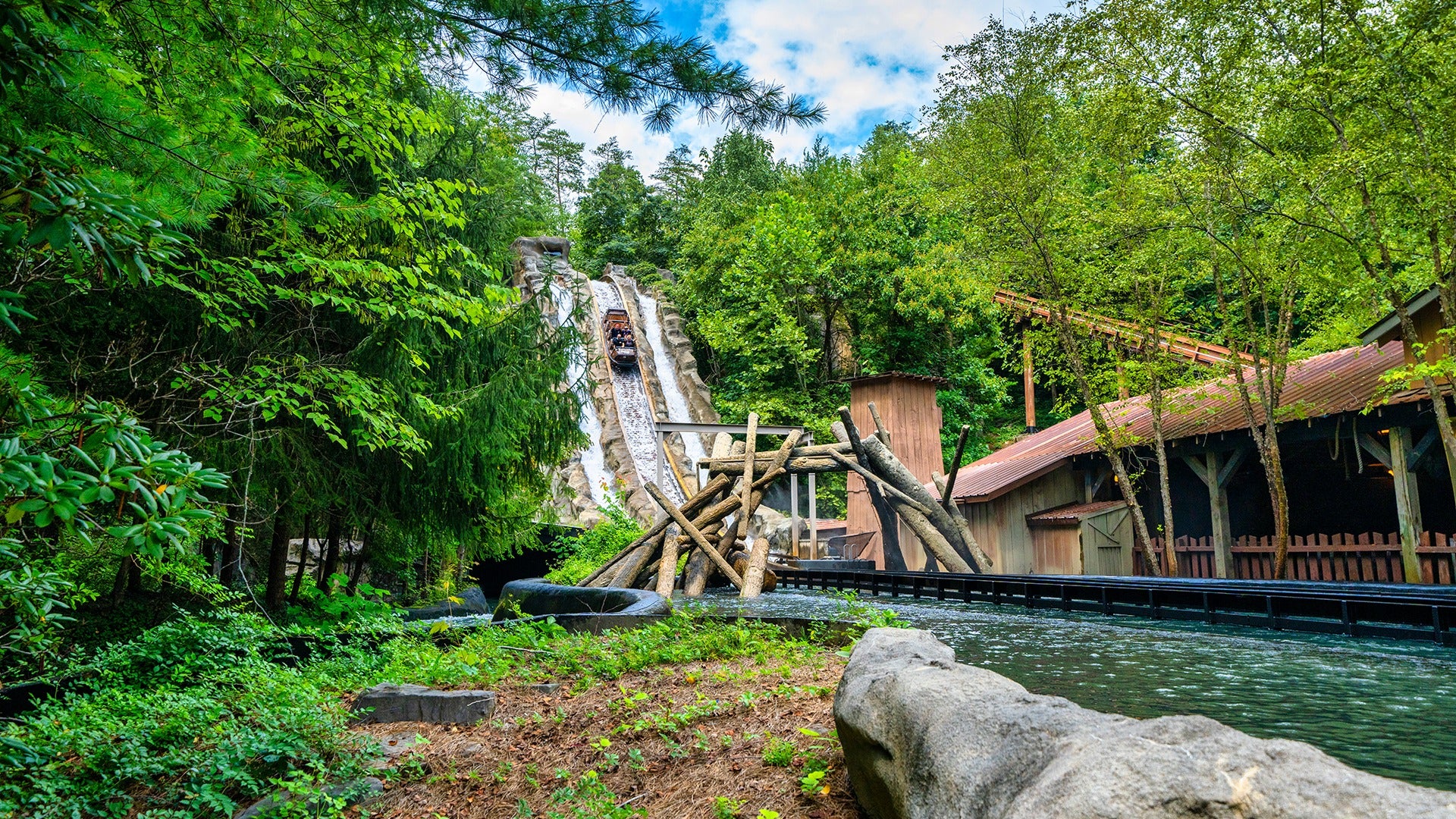 Log boat emerging from Daredevil Falls’ final plunge, water spraying dramatically over riders’ heads