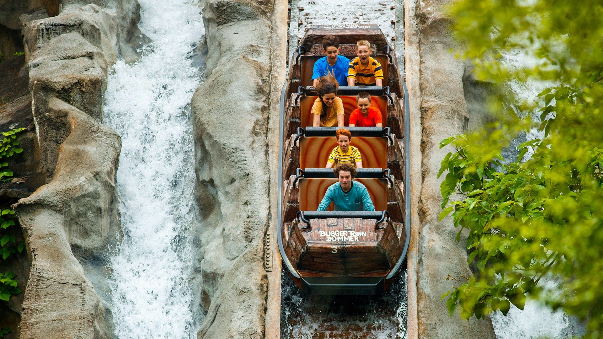 Action shot of Daredevil Falls log descending the waterfall, riders gripping the sides