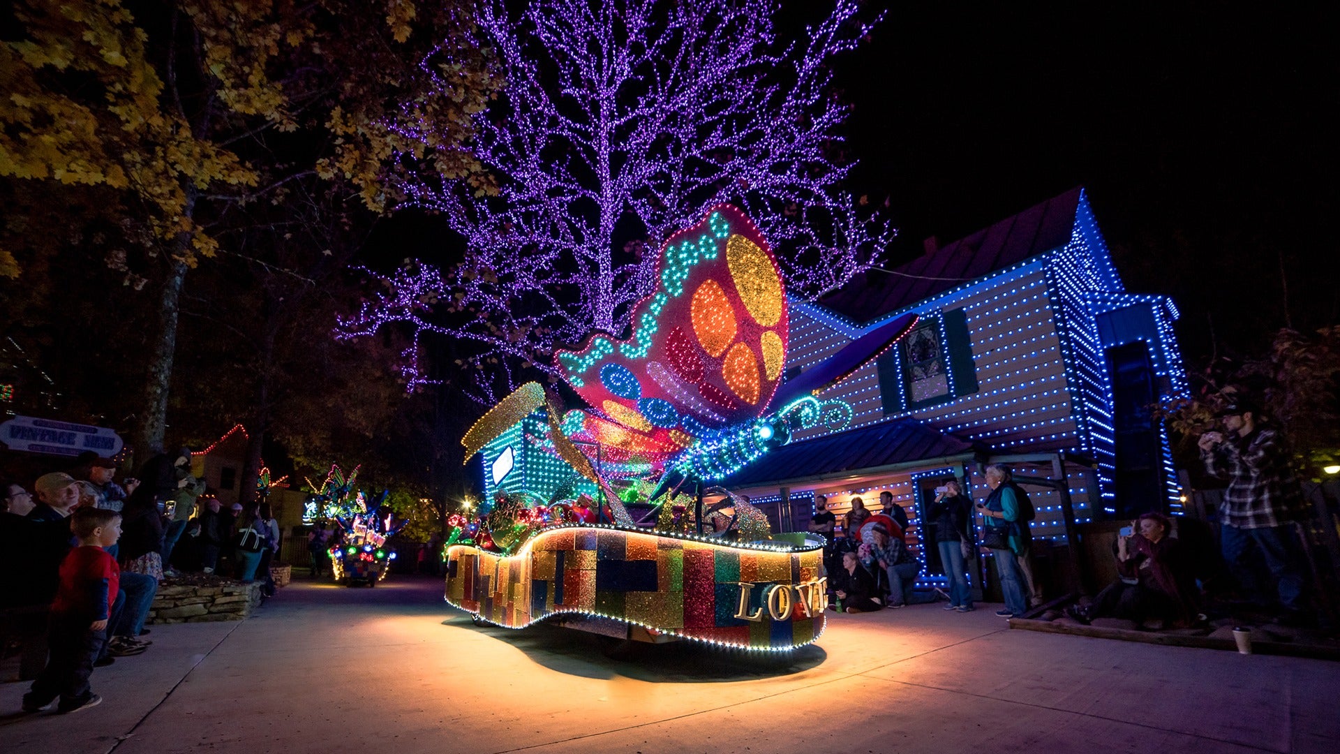 a colorful parade of lights with people watching