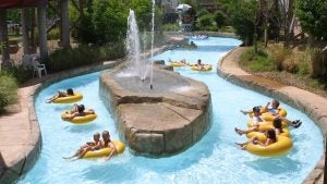 people on floaties floating down a lazy river with a fountain in the middle