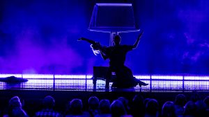 a magician with his assistant on stage and an audience watching
