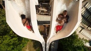 two boys going down a high slide in a waterpark