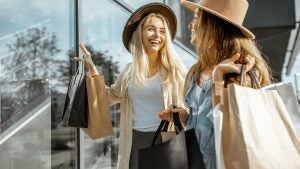 two women holding paper bags going shopping