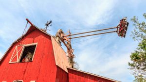 a red barn with a swing ride and passengers in a theme park