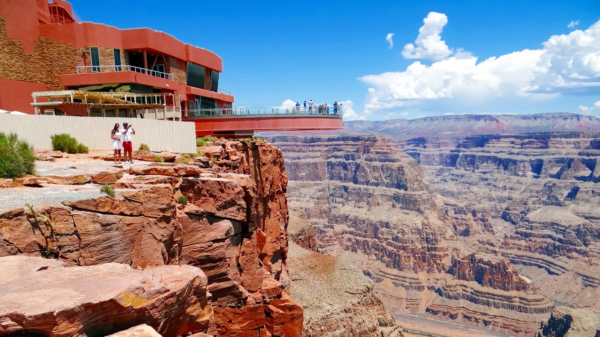 people on an observation deck looking out at the grand canyon below