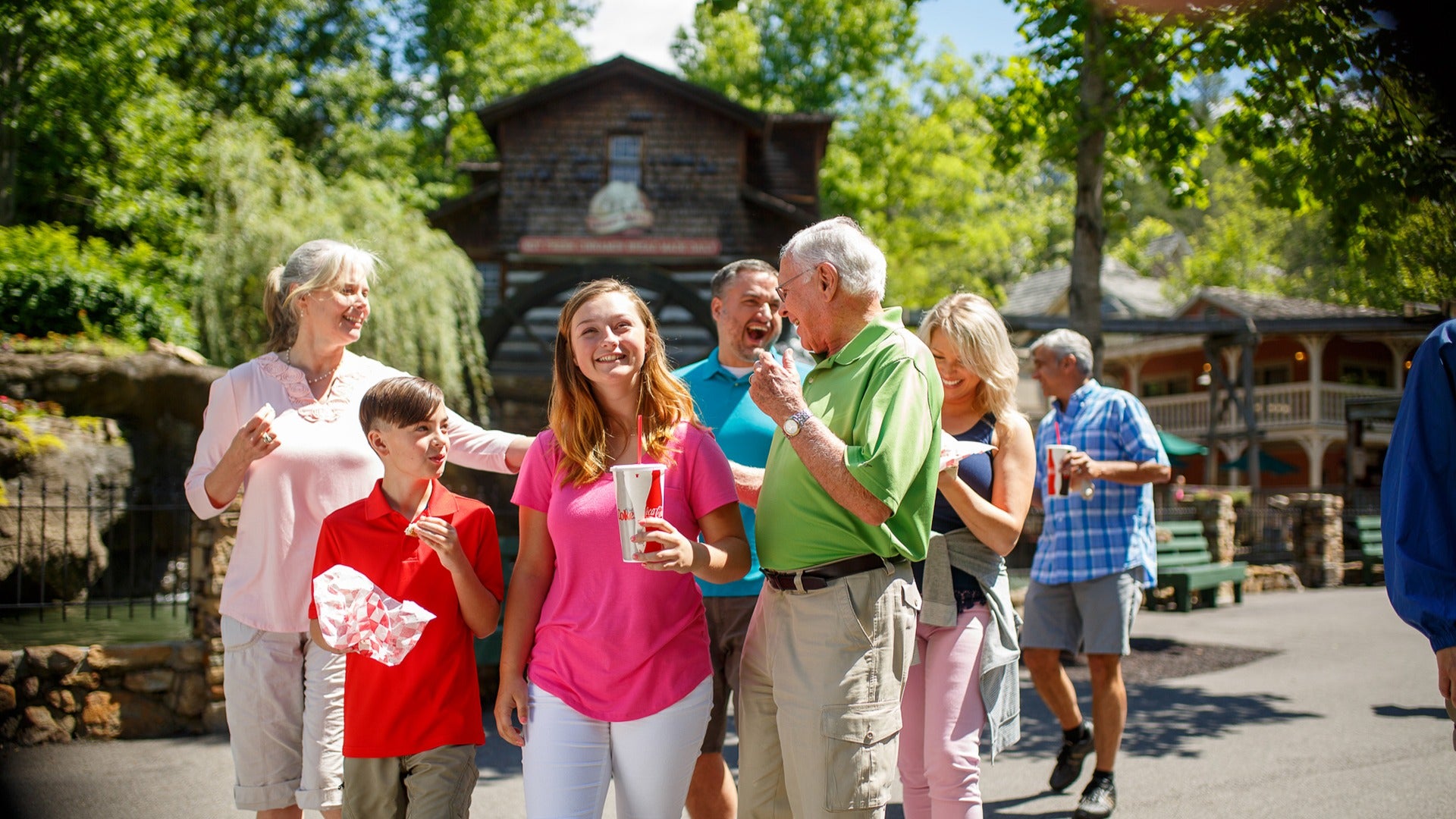 a family eating and drinking while walking around grist mill in dollywood