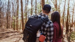 a couple hiking, man wearing backpack with portable speaker