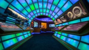a tunnel of different colored light panels with exhibits on display