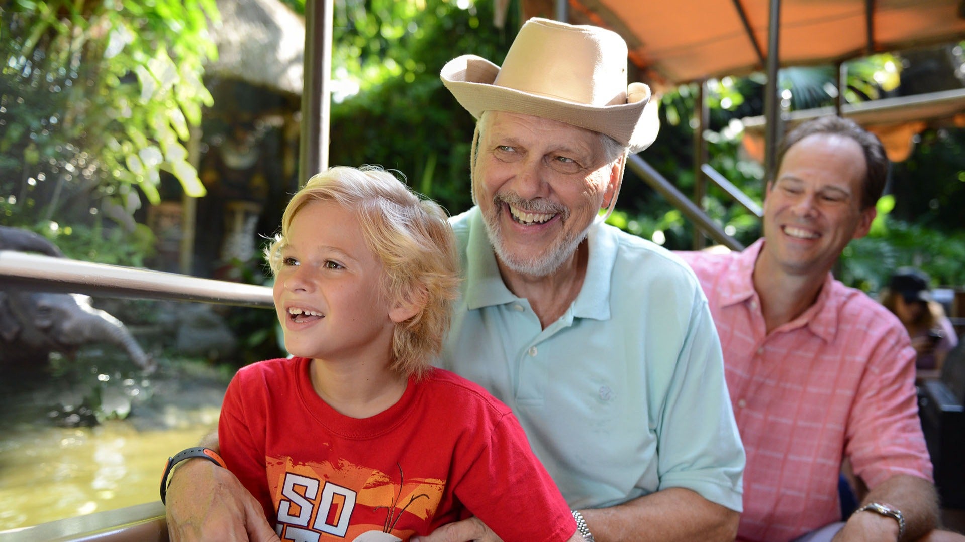 granda and grandson riding an amusement park ride along a river