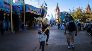 a kid holding a mickey shaped light stick with his parents walking down disney