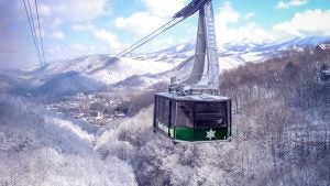 a tramway going up a snowy mountain with passengers on board