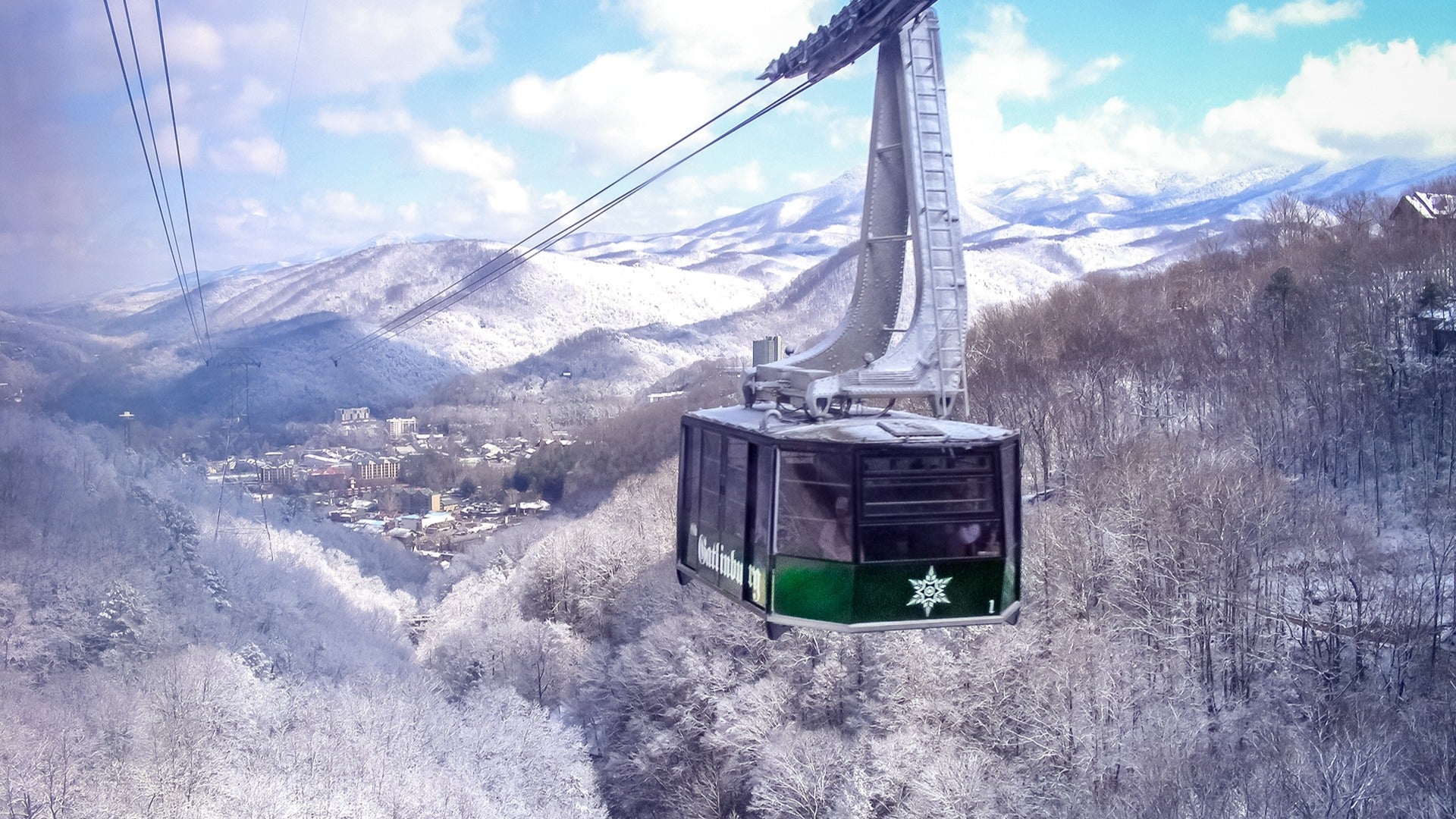 a tramway going up a snowy mountain with passengers on board