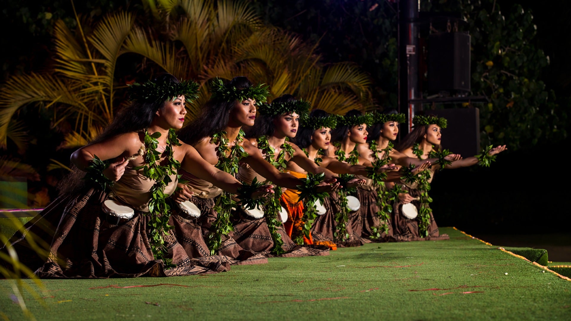women performing in a luau with headdresses and leis