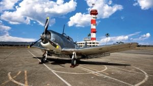 airplane on a tarmac with a lighthouse at the back and a USA flag