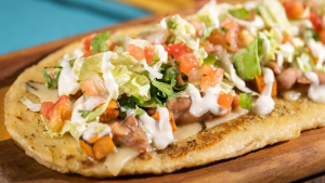 a flatbread topped with veggies and meat with sauce