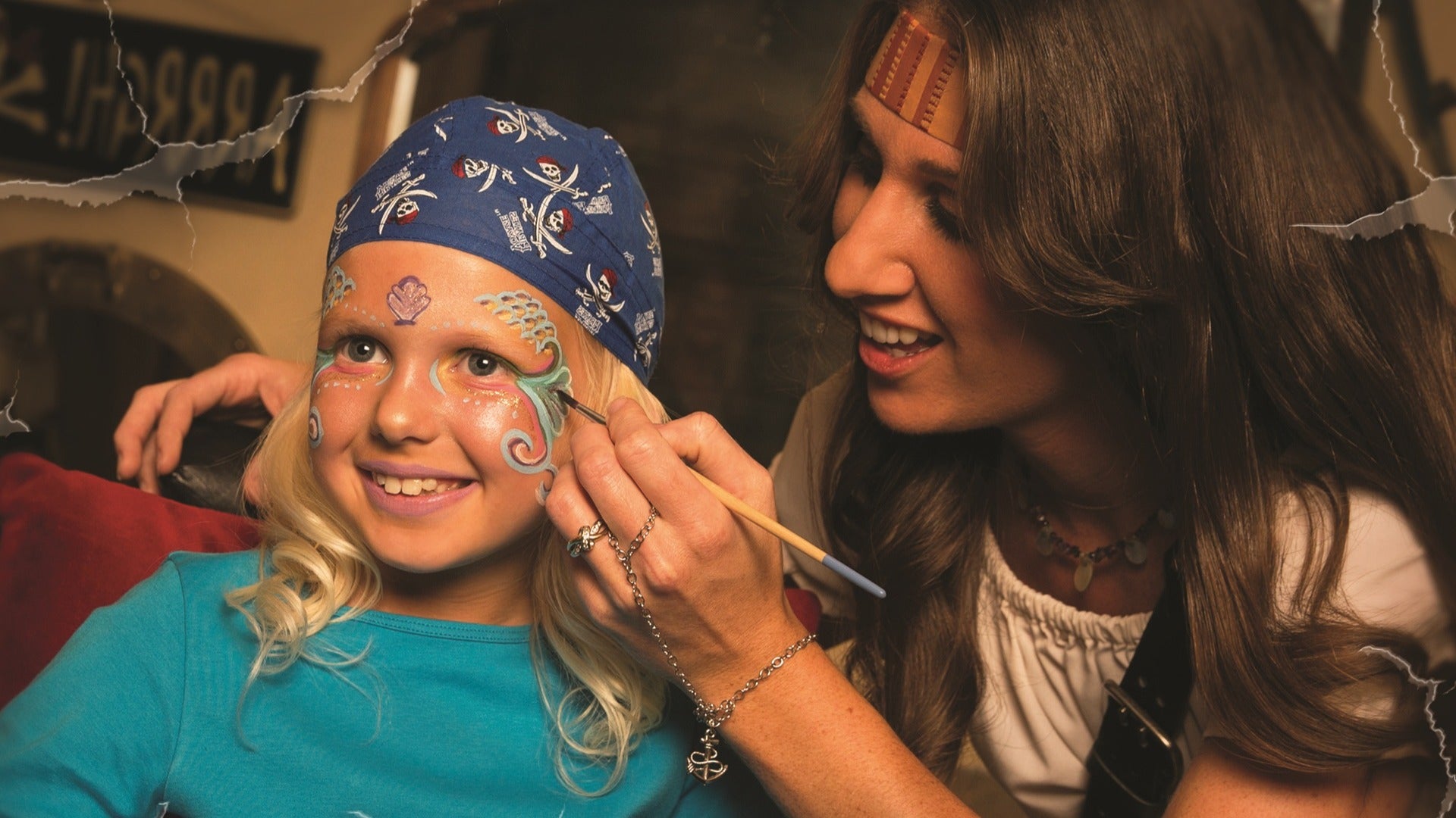 a woman face painting a child dressed as a pirate