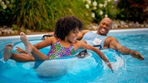 father and daughter on floaties enjoying in the pool