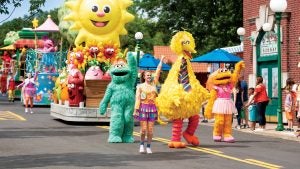 sesame street characters big bird and oscar the grouch on a parade with people watching on the sidelines