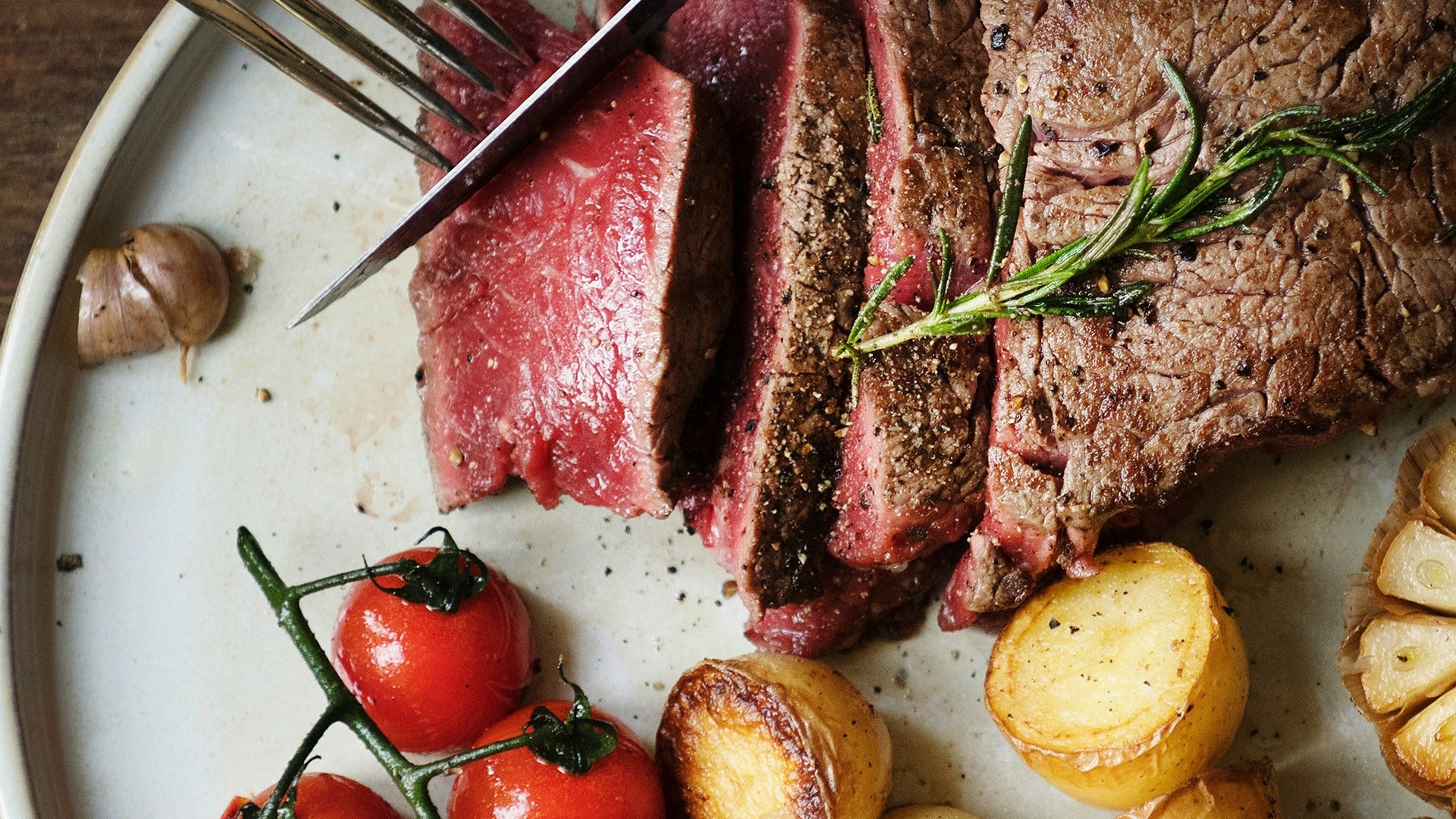 steak served with tomatoes. potatoes, and garlic