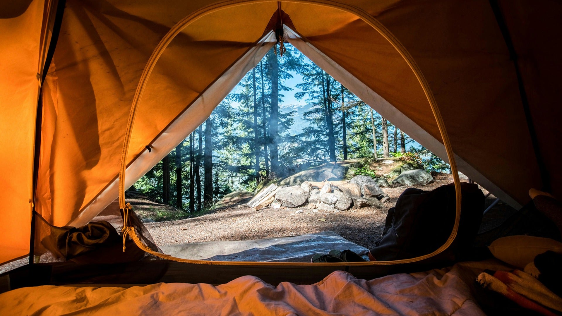 a tent in a forest overlooking a fire pit
