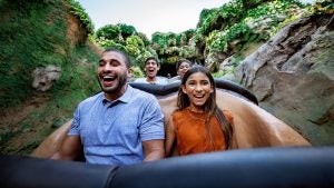 people in a roller coaster riding through a mossy path