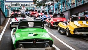 cars on a starting line of a speedway with people watching on the sides