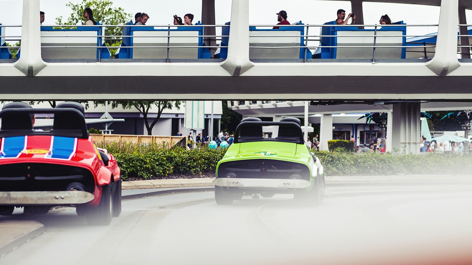 cars on a speedway ride with people above sitting and watching