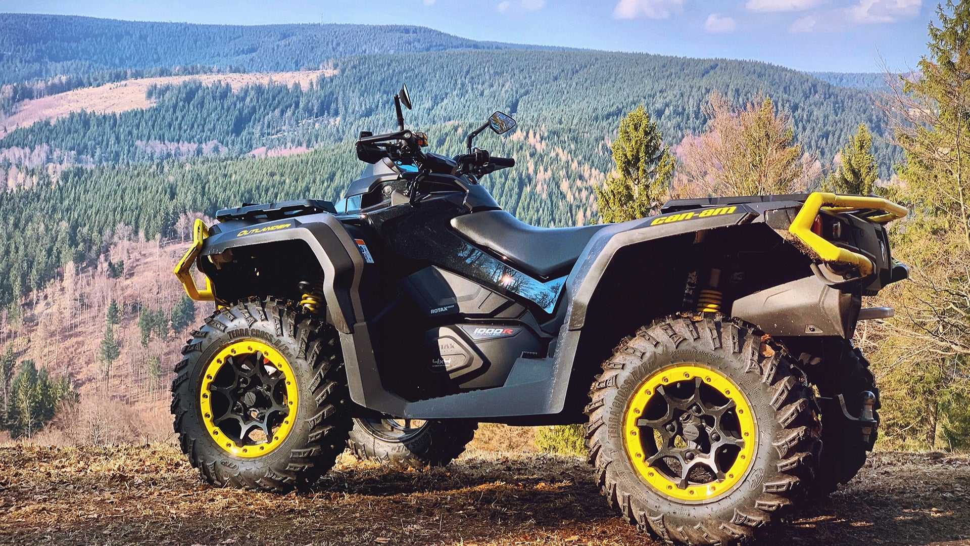 an atv parked on a cliff with a view of the mountains at the back