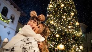 a woman hugging a child in front of a big christmas tree