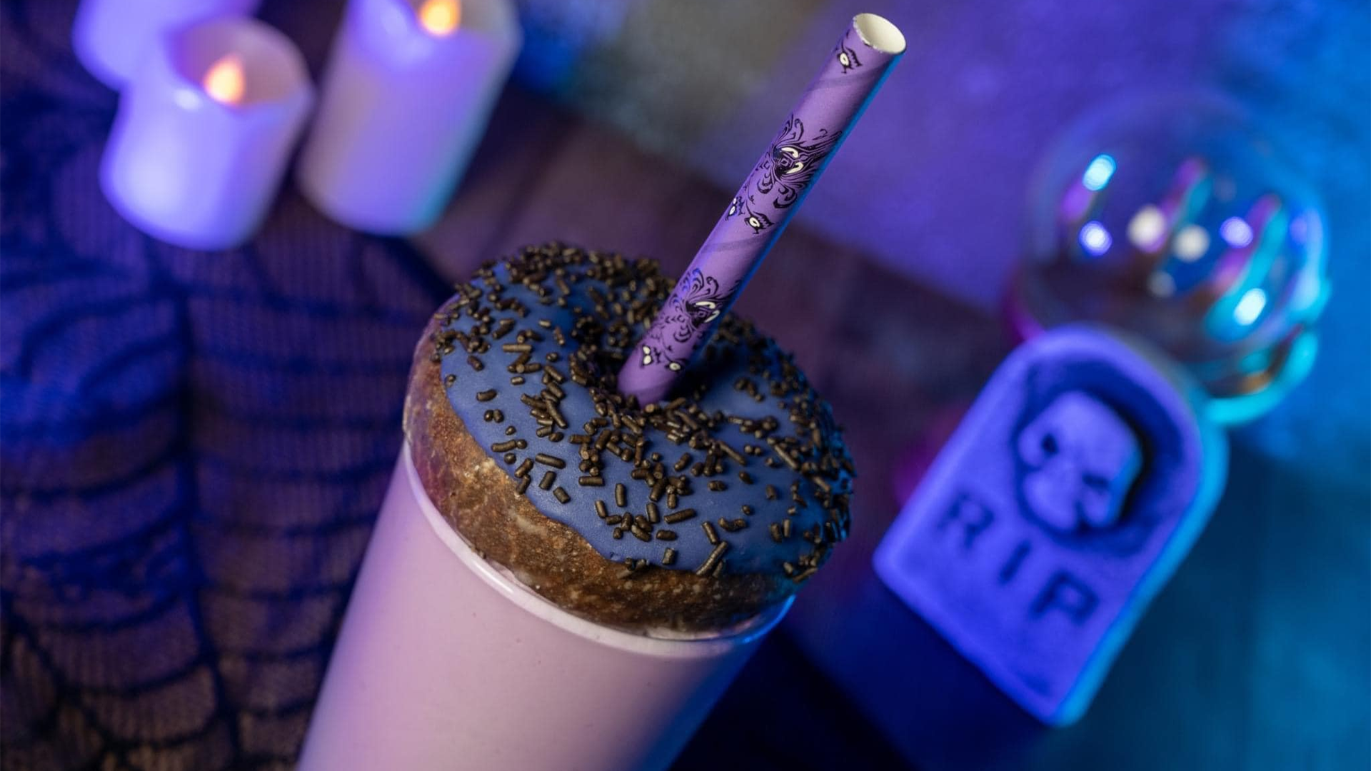 a milkshake topped with a blueberry glazed donut with an intricately designed straw