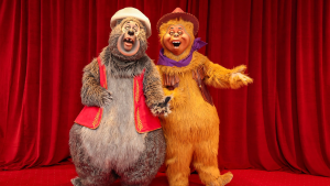 two cowboy-dressed bears with a red curtain at the back