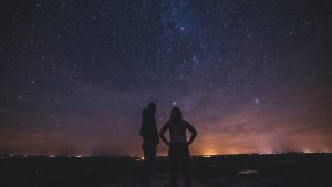 a couple stargazing with city lights below