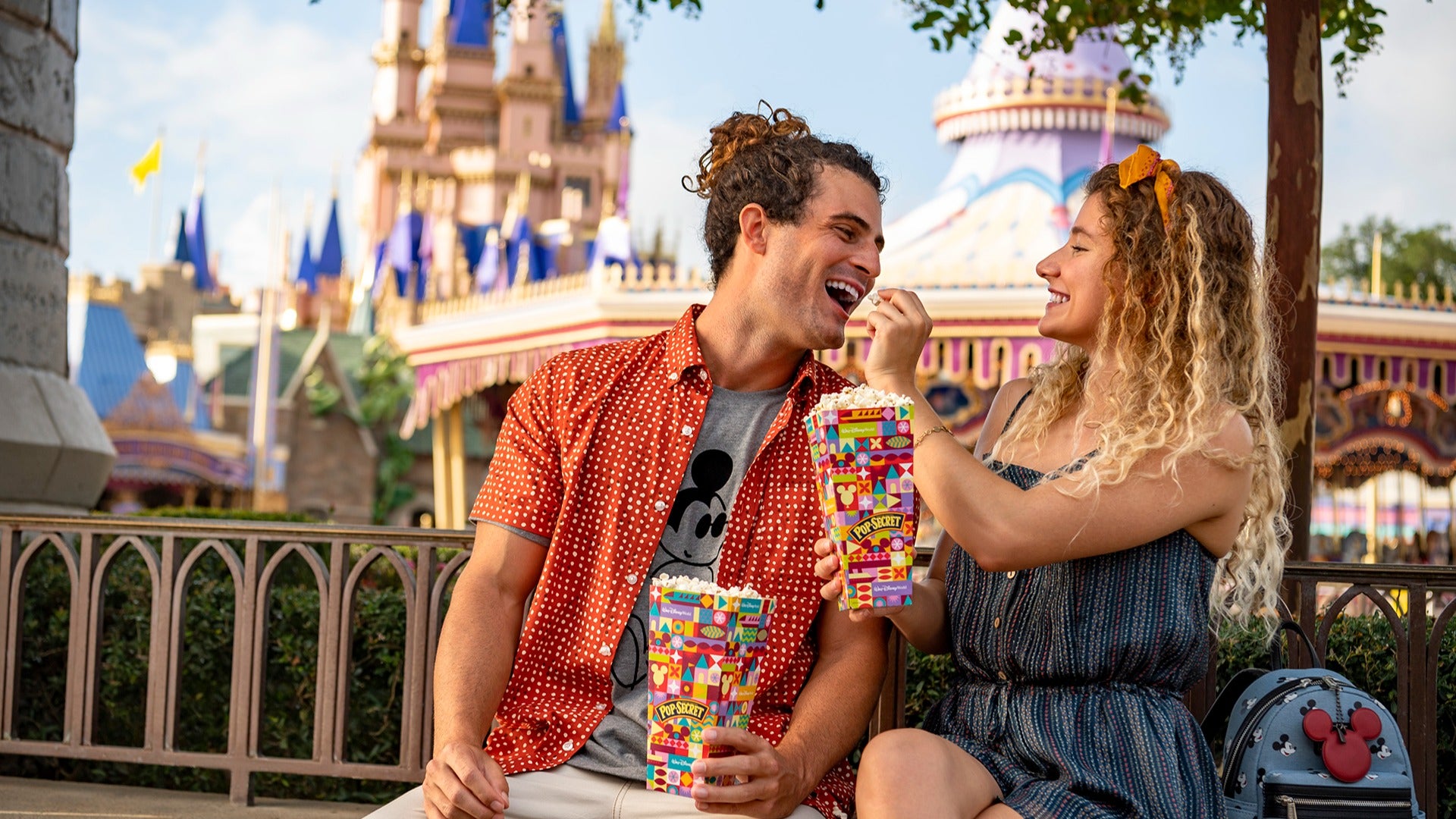 a couple eating popcorn together with cinderella's castle at the back in disney world
