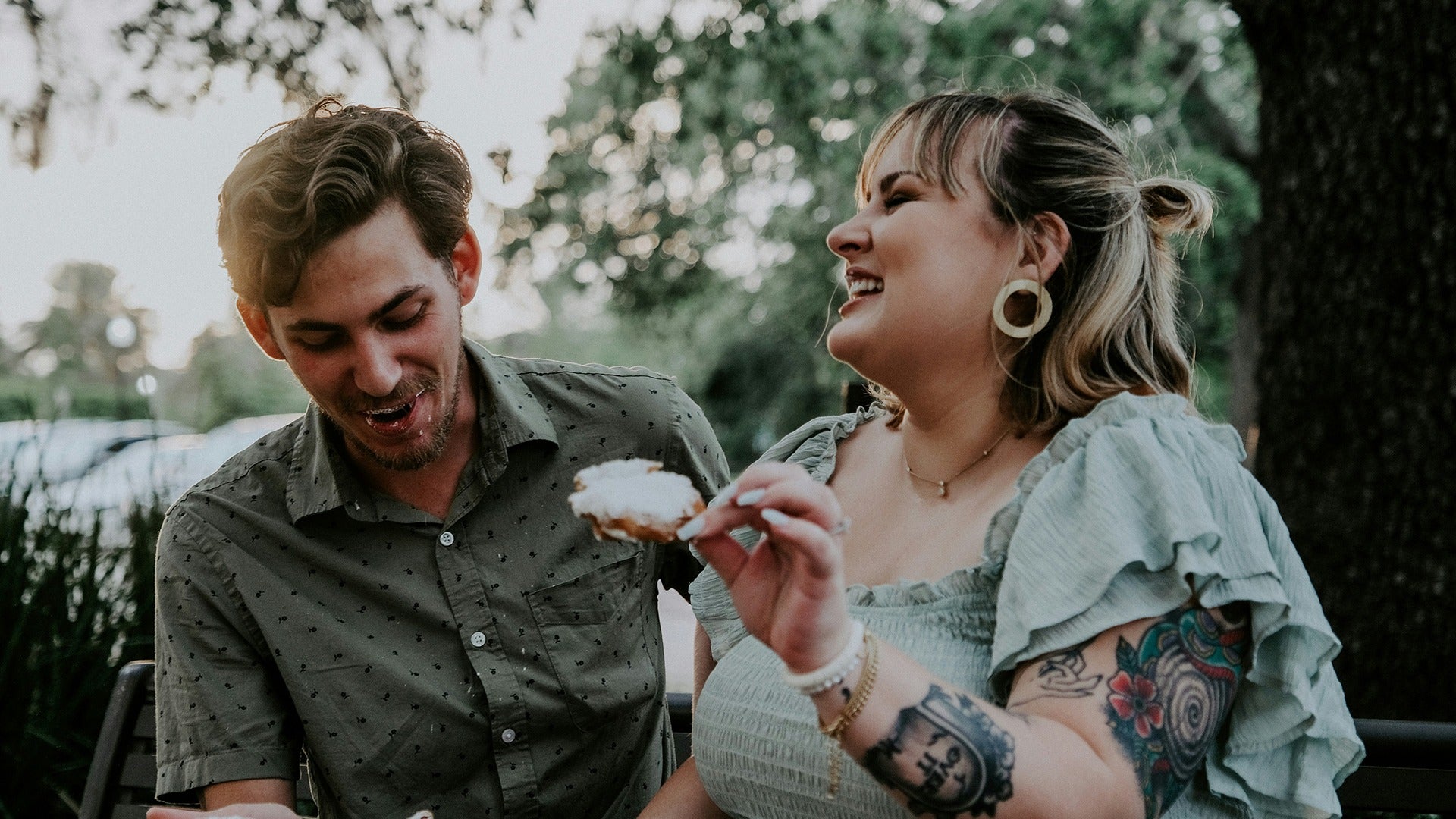 a couple eating beignets at city park, new orleans