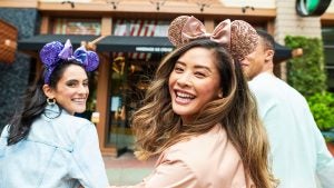 friends looking back and smiling while wearing mickey ears