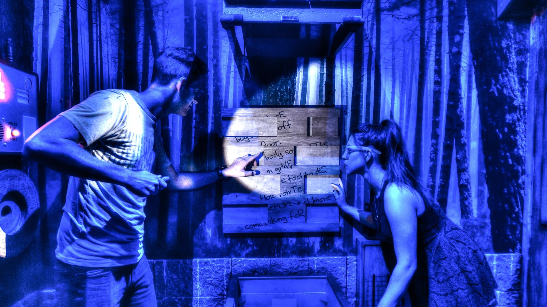 man and woman in an escape room, shining a flashlight on clues