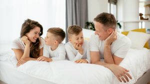 a family with parents and two kids on a hotel bed