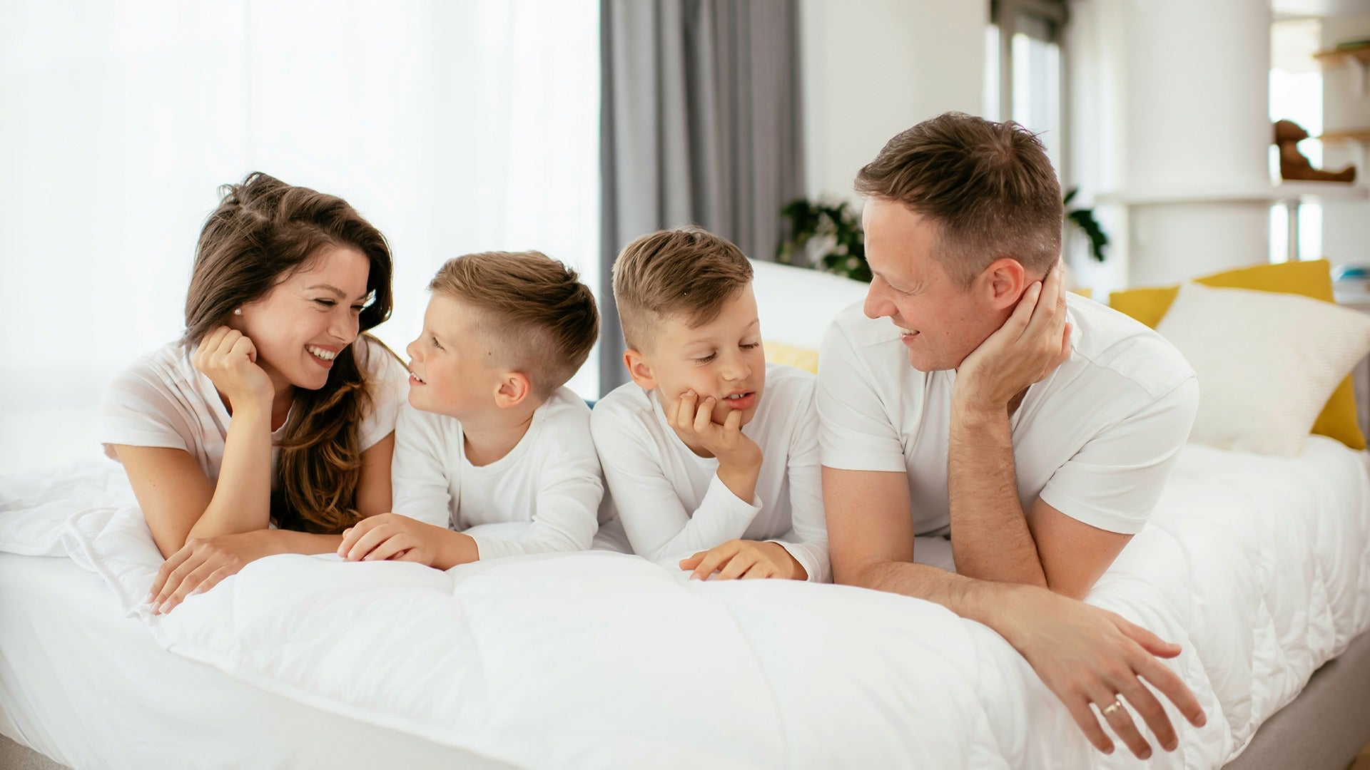 a family with parents and two kids on a hotel bed