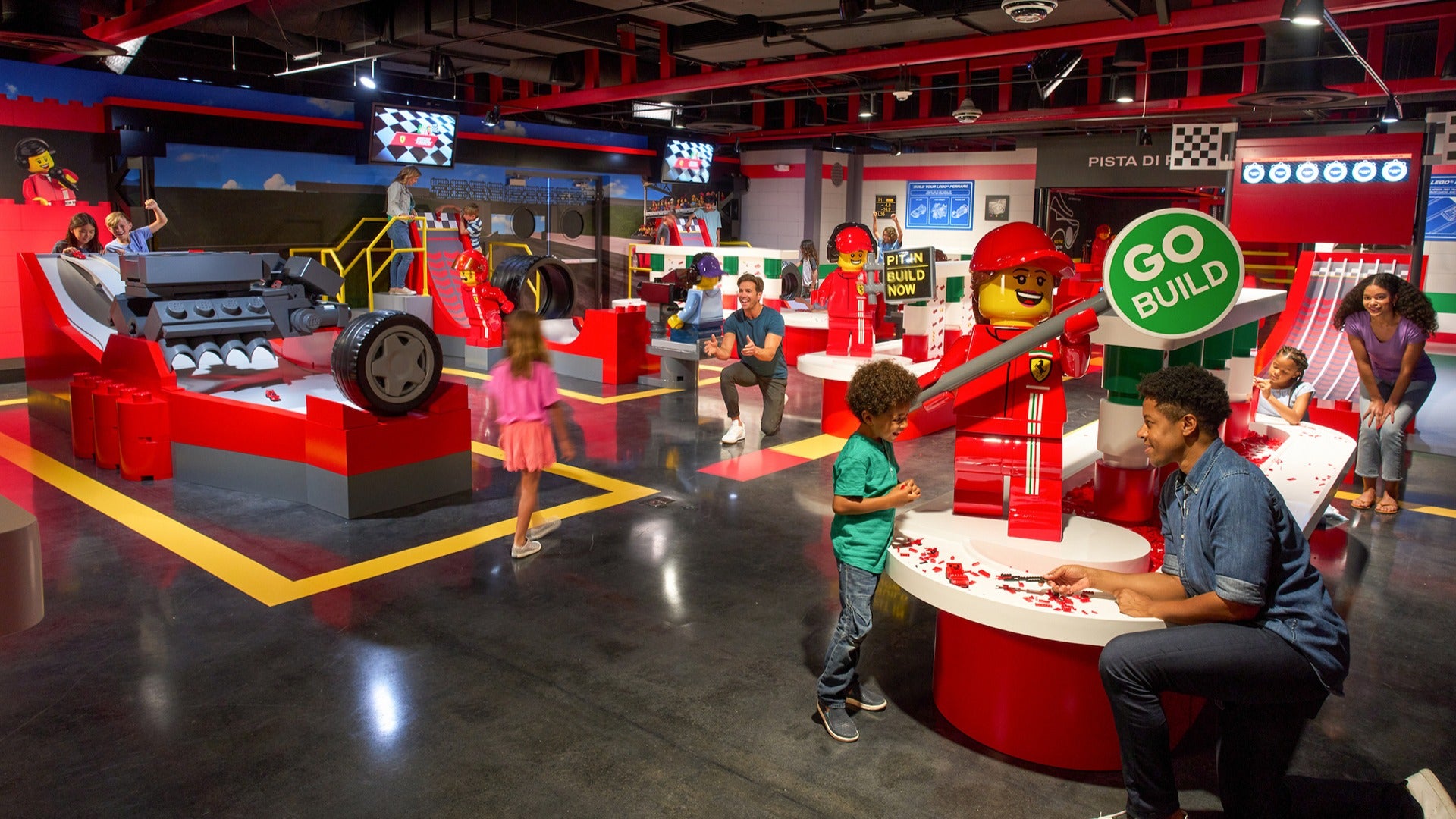 parents and kids playing a car themed build area with legos