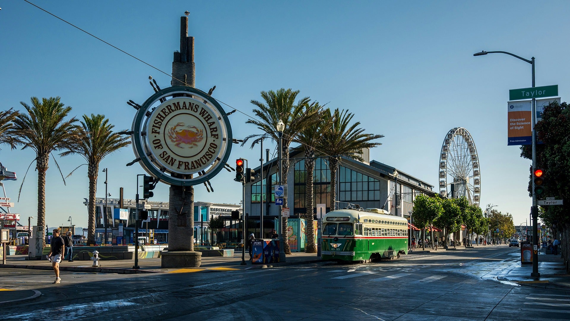 a boardwalk with people walking, a tram, and a view of a ferris wheel at the back