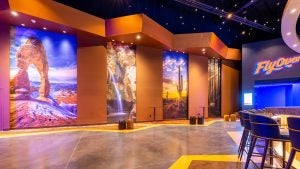an entrance hall with photos of various locations, a bar with stools, and a signage of the flyover las vegas