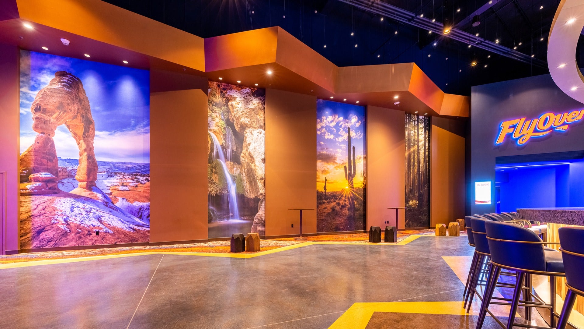 an entrance hall with photos of various locations, a bar with stools, and a signage of the flyover las vegas