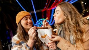 two girls eating churros at a theme park