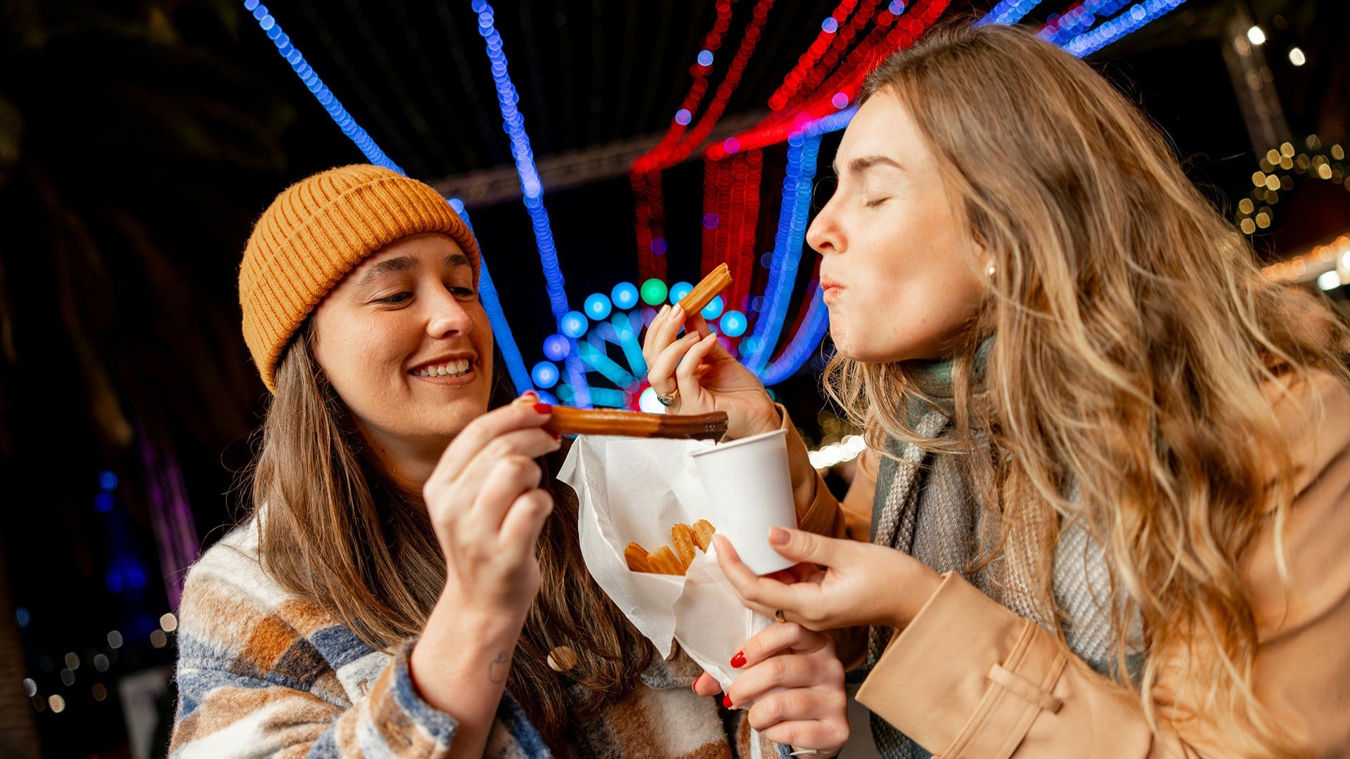 two girls eating churros at a theme park