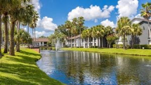 a row of resorts with a river running down the middle and a bridge, surrounded by trees