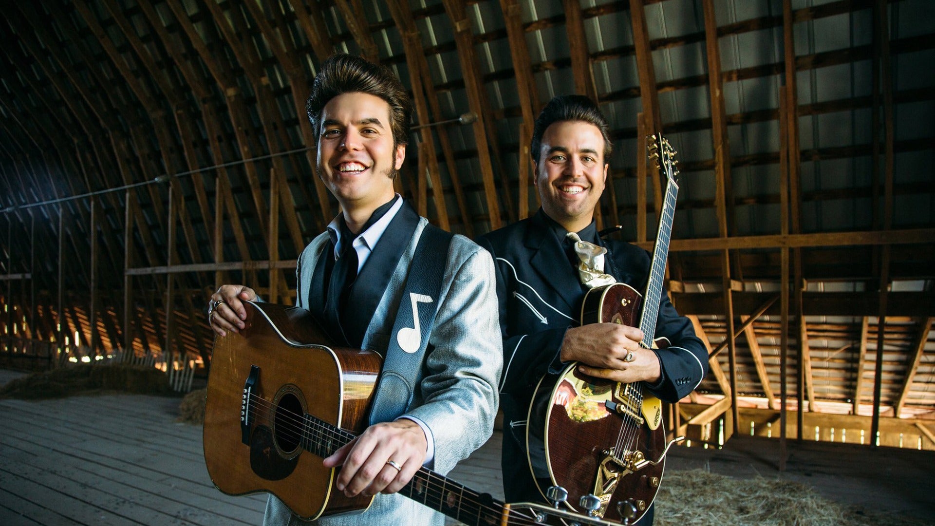 two musicians holding instruments in a barn